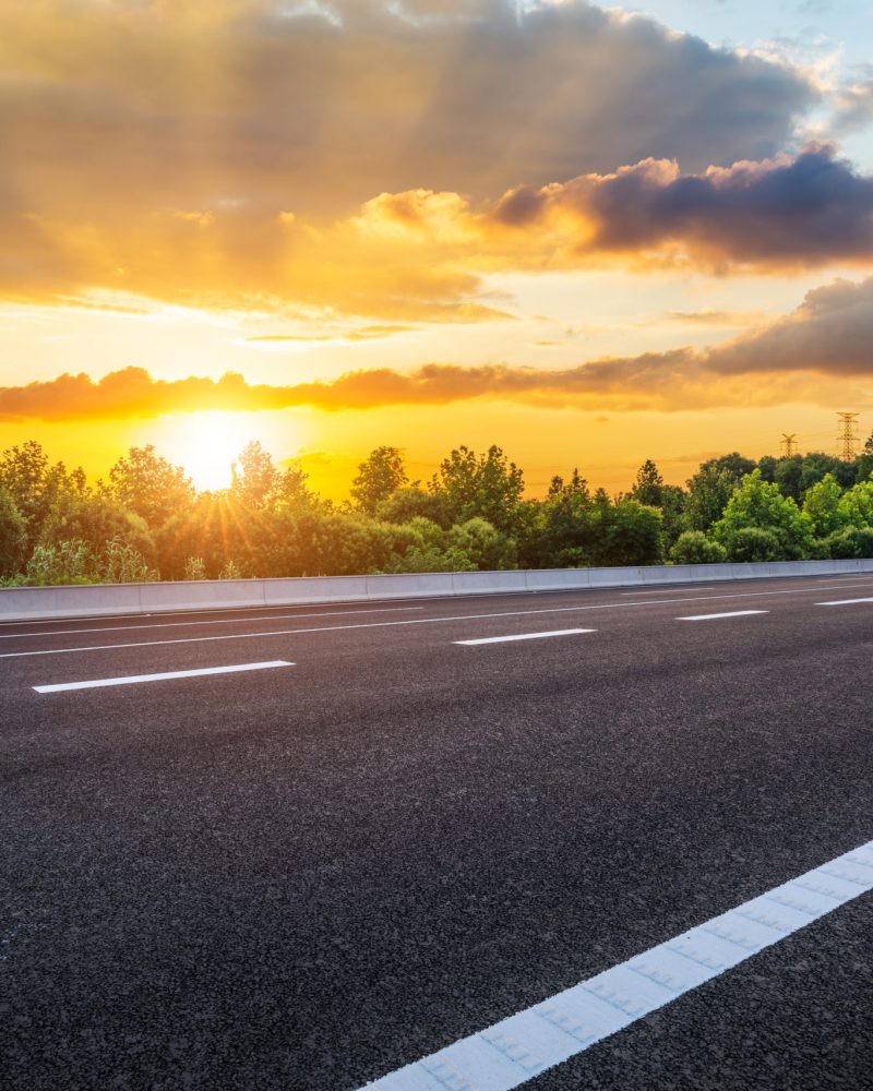 Empty asphalt road and green forest with beautiful sky clouds at sunset